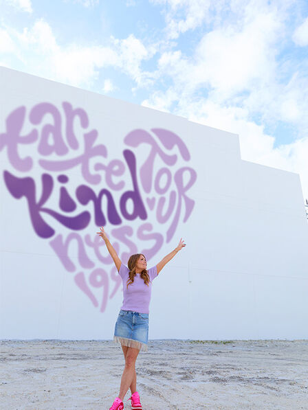 Maureen Kelly in front of wall with kindness tour logo